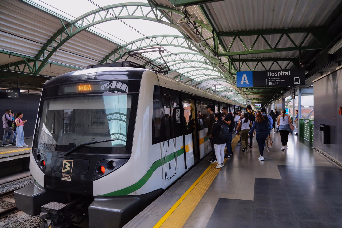Estación Hospital del Metro de Medellín con tren de la Línea A y pasajeros, ubicada cerca de Prado Centro y de los apartamentos amoblados de Nook Cool Living