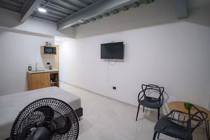 Zona de descanso con televisión y mesa para dos personas en estudio amoblado