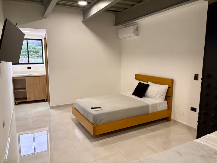 Habitación moderna con cama doble y techo industrial en apartamento amoblado