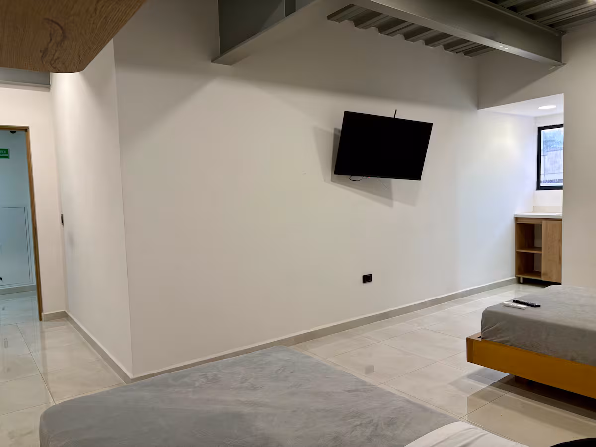 Vista interior del estudio con televisión de pared y cama doble en Medellín