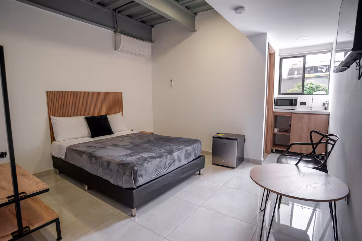 Estudio amoblado en Medellín con cama doble, escritorio y cocineta junto a la ventana