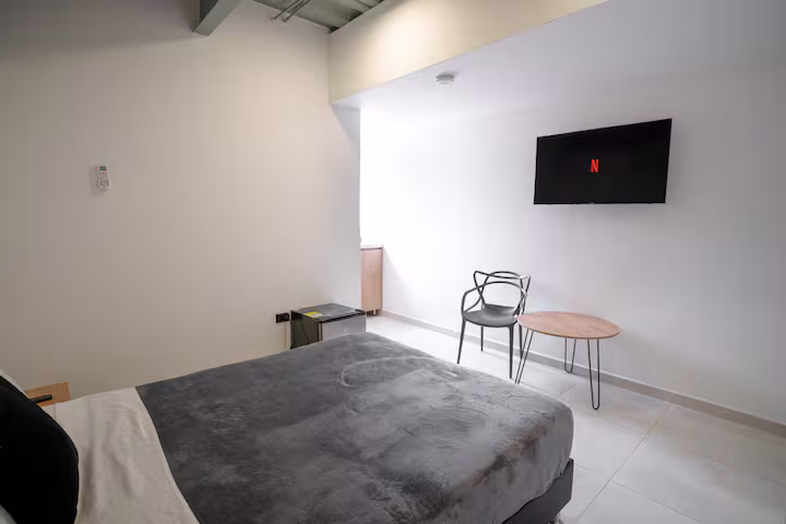 Dormitorio con cama doble, televisión de pared y mesa auxiliar en apartamento amoblado