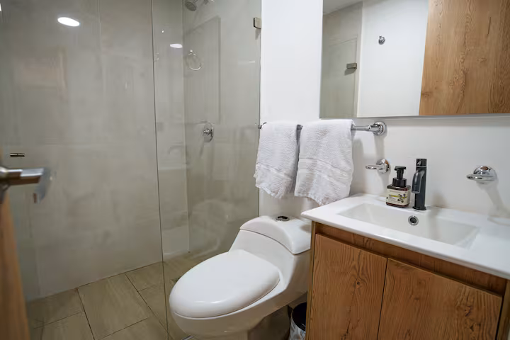 Baño privado moderno con ducha de vidrio y lavabo sobrepuesto en Medellín