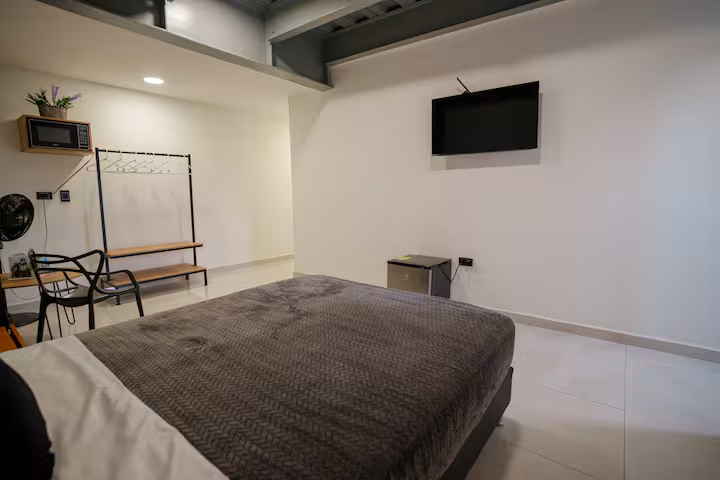 Dormitorio moderno con televisión en apartamento amoblado de Medellín